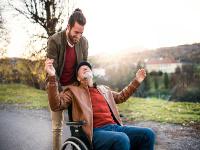 Image of young man pushing an older man in a wheelchair