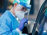 Image of person in PPE taking swab from occupant in a car