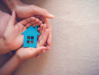 Image of people holding a small house in their hands