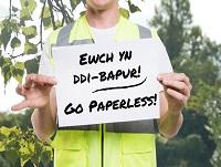 A man holding up a sign saying 'Go paperless'