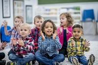 A group of children sitting on the floor clapping