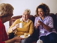 Image of a carer having a cup of tea with 2 ladies