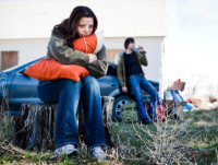 A homeless couple by a car