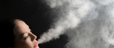 The picture shows a woman exhaling a large amount of smoke from her mouth.