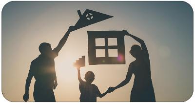 Black silhouette of a family of 3 each holding a cut out piece of a house with the sun shining through in the background