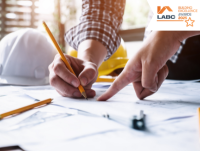 Image of a two people with technical drawings and a hard hat in the background