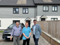 Image of three people outside a house