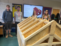 Image of four people with a dog kennel